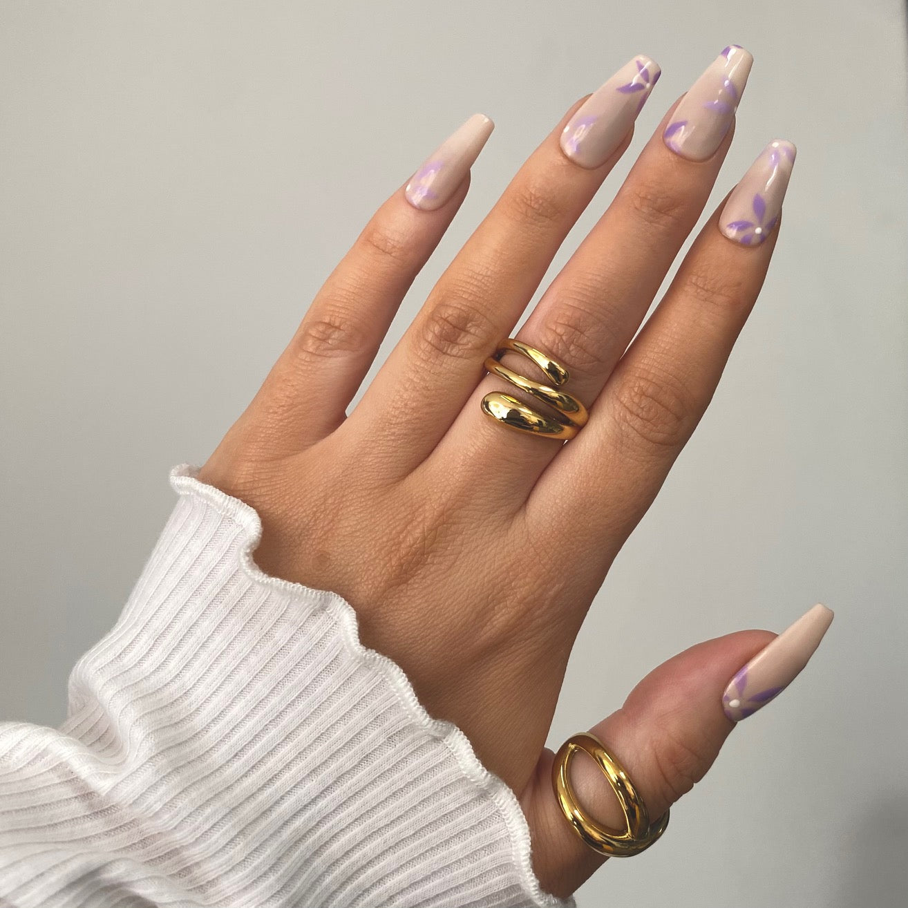 a hand wearing chunky gold wrap style ring and alternate statement ring