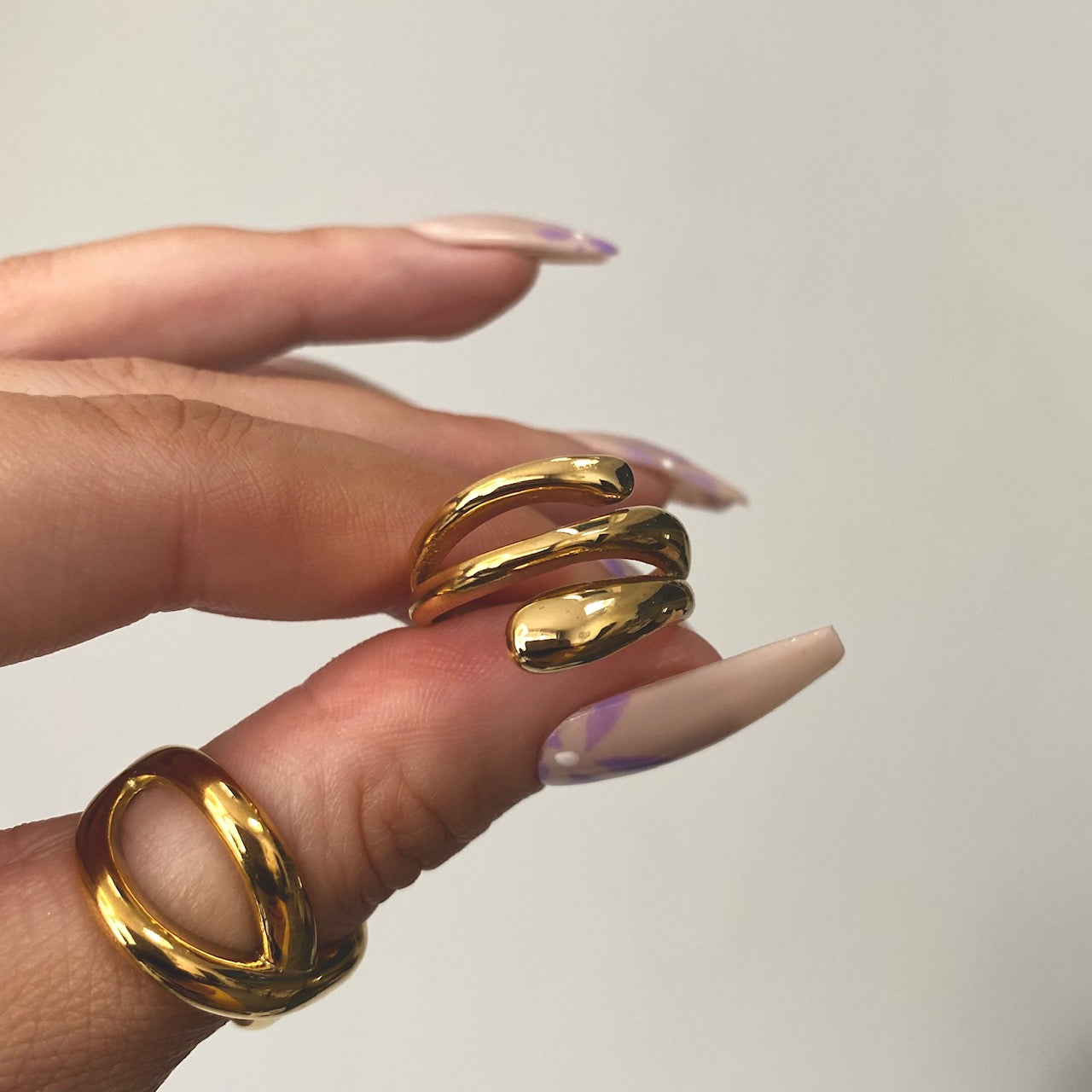 a hand holding chunky gold statement ring in wrap style